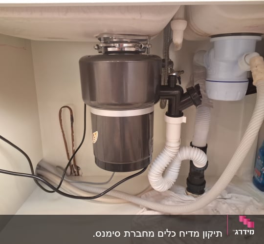 מכשיר טוחן אשפה מתחת לכיור עם חיבורים חשמליים